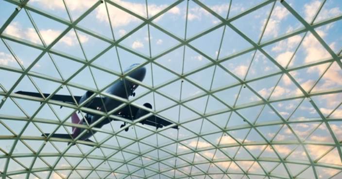 An airplane flying above a pre-engineered metal structure.