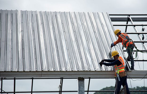 Image of workers fixing industrial roofing sheets.