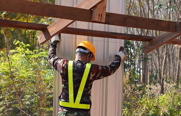 A construction worker working in a site holding a sheet for roofs.