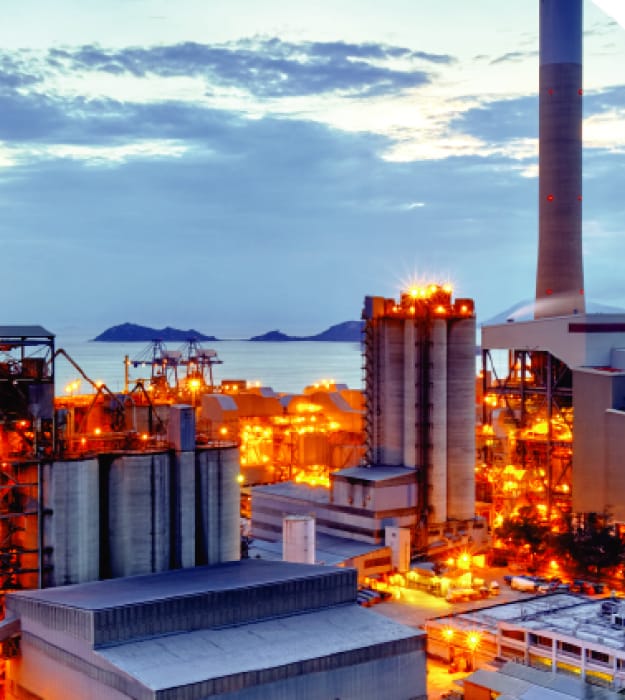 The evening view of a power plant with huge metal storage and pipe structures.