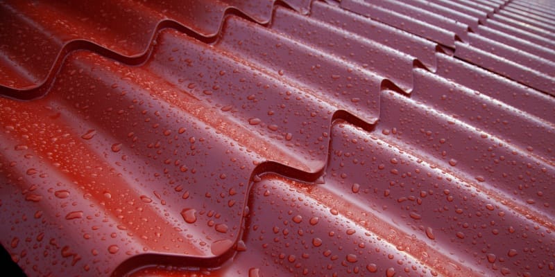 Raindrops on a metal roof sheet illustrating concerns about rain noise on metal roofing.
